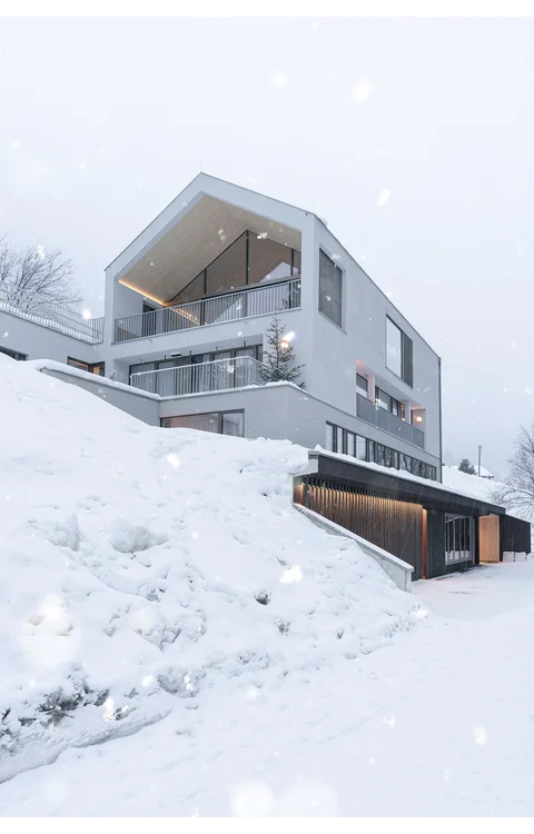 Das moderne Gebäude der Omaela Apartments im Schneefall, beleuchtet, in St. Anton am Arlberg