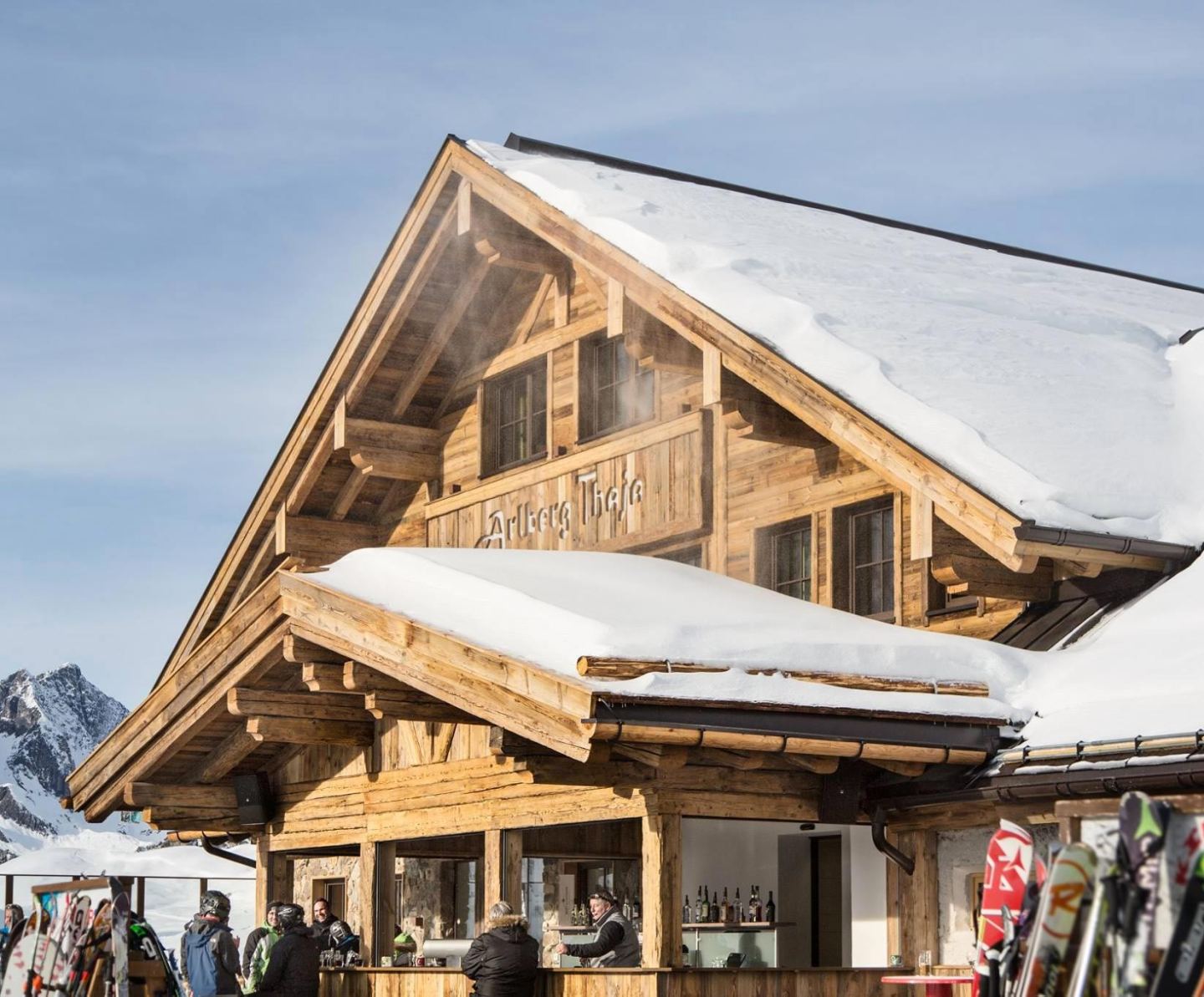 Skihütte Arlberg Thaja im Schnee mit Sonnenterrasse und Ski an einem Wintertag