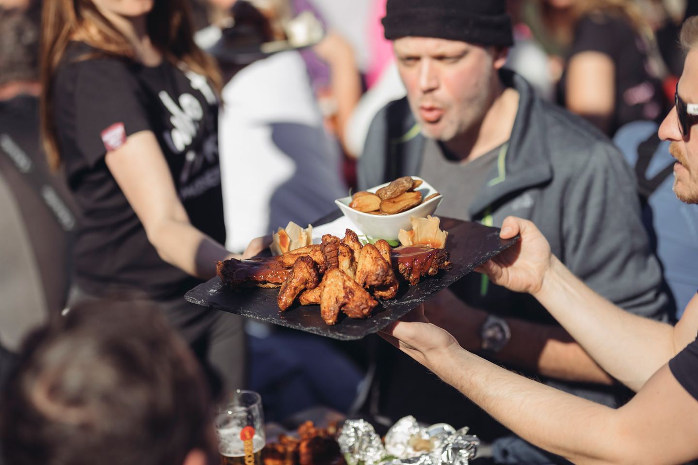 Après-Ski am Mooserwirt: Bedienung serviert eine Platte mit Chicken Wings und Spareribs