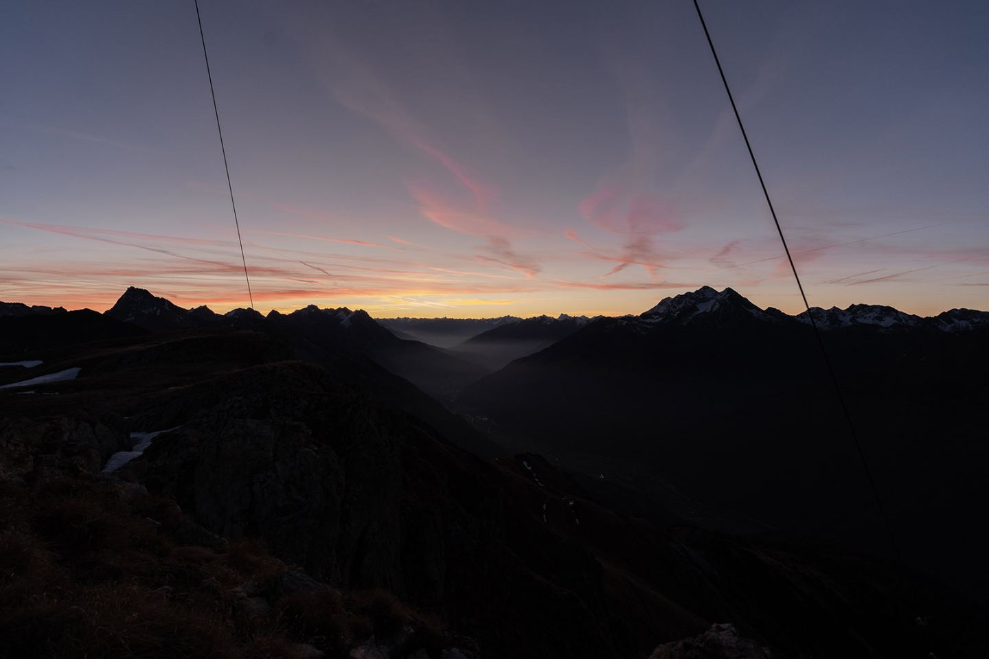 Morgenrot über den Bergen am Arlberg – rosa gefärbter Himmel über dunklen Gipfeln und Tal