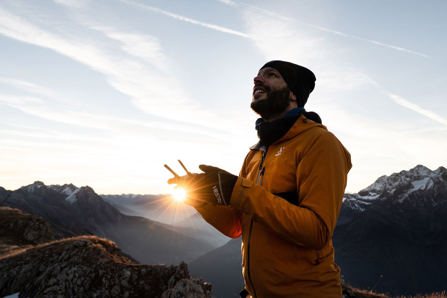 Bergsteiger am Gipfel hält die aufgehende Sonne in der Hand, St. Anton am Arlberg