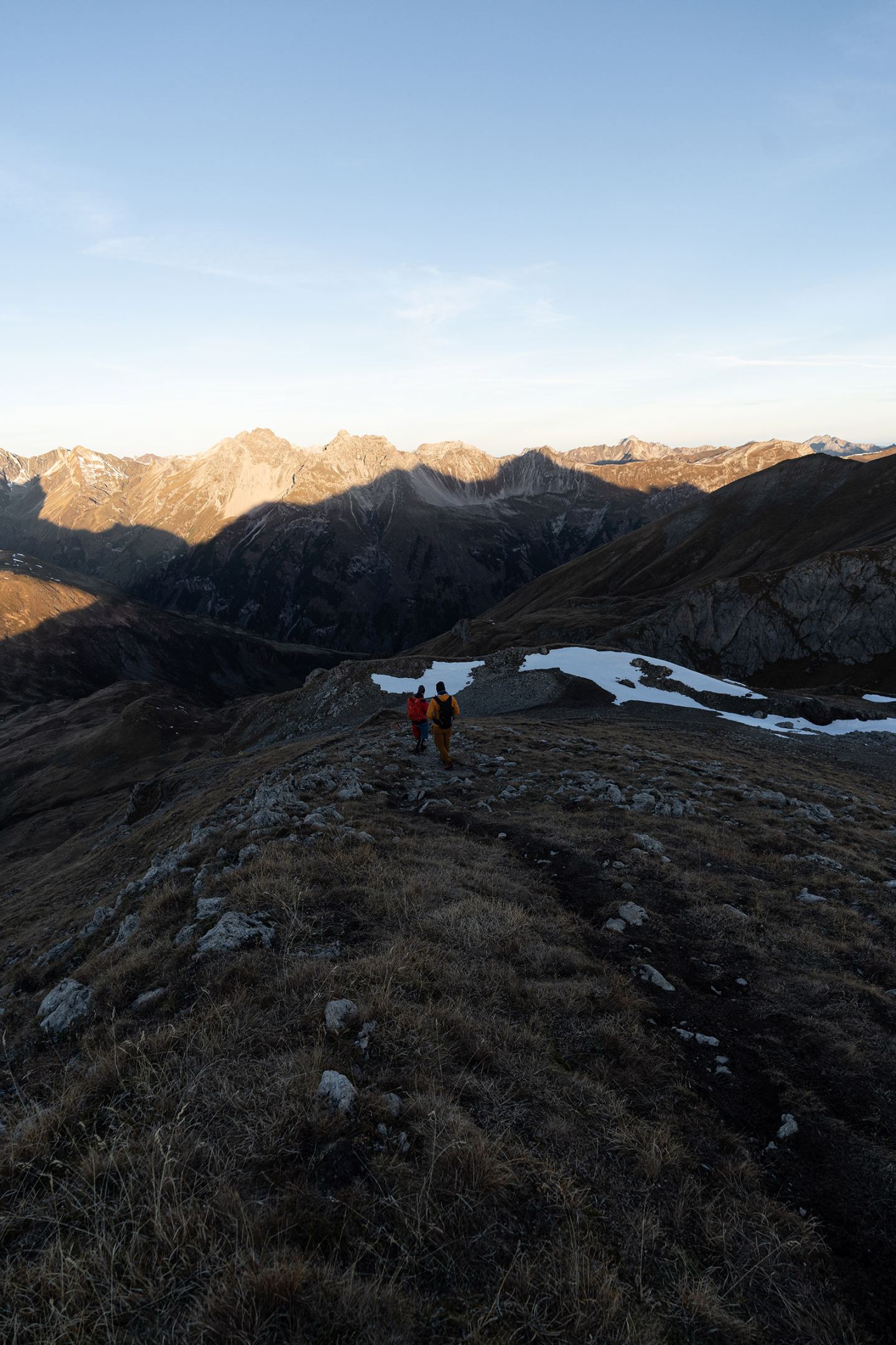 Zwei Wanderer am Berggrat im Morgenlicht mit Bergpanorama am Arlberg