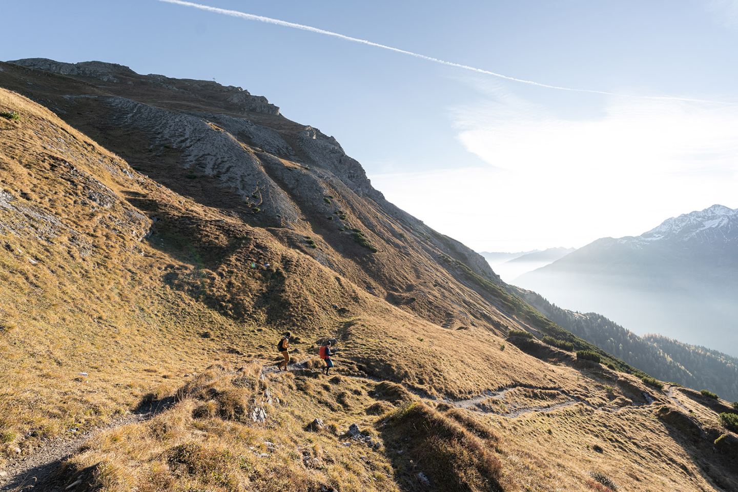 Zwei Wanderer auf sonnigem Bergpfad über dem Nebeltal bei St. Anton am Arlberg