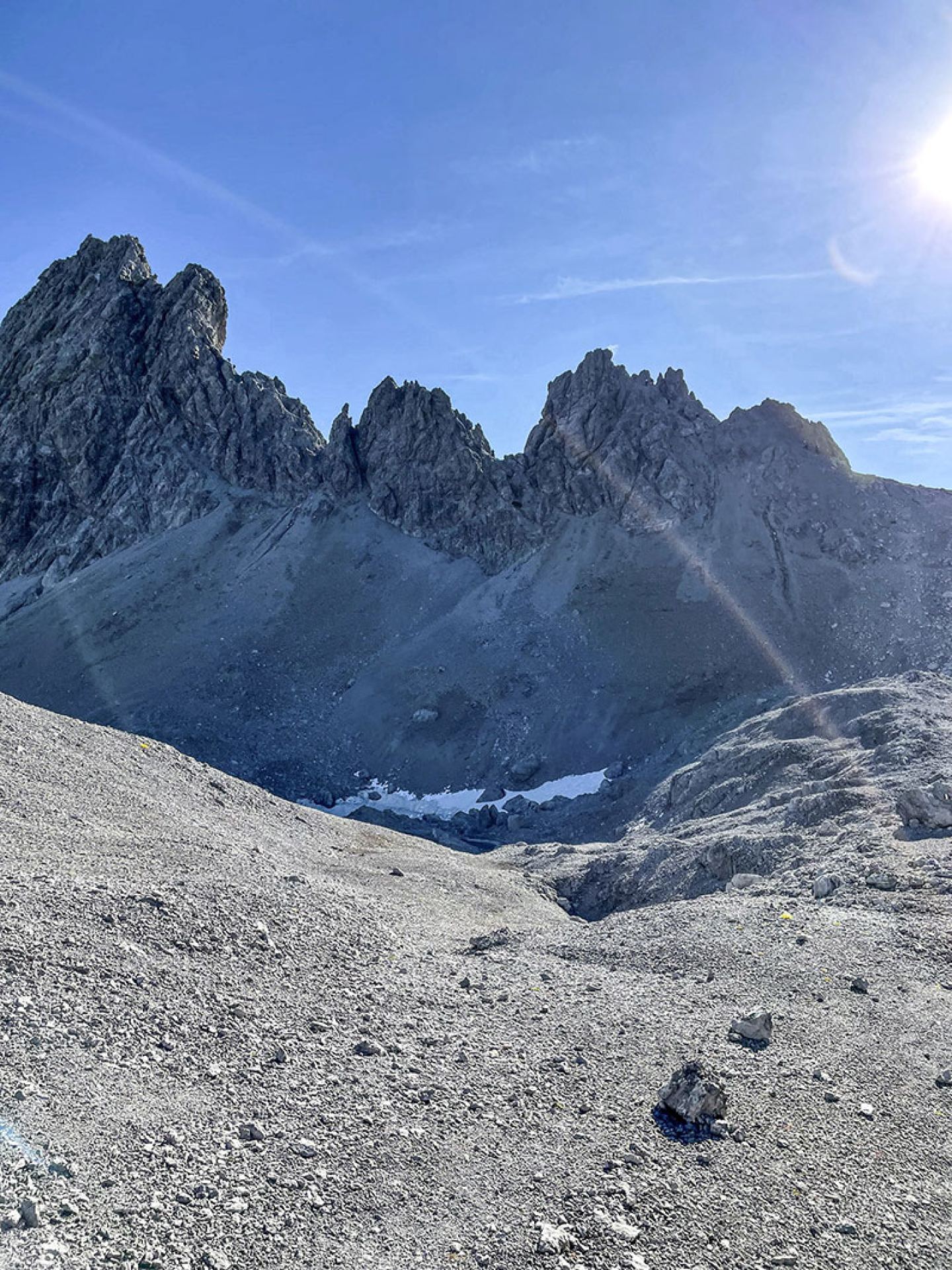 Jagged rocky peaks and scree slope on the Arlberg via ferrata under a blue sky