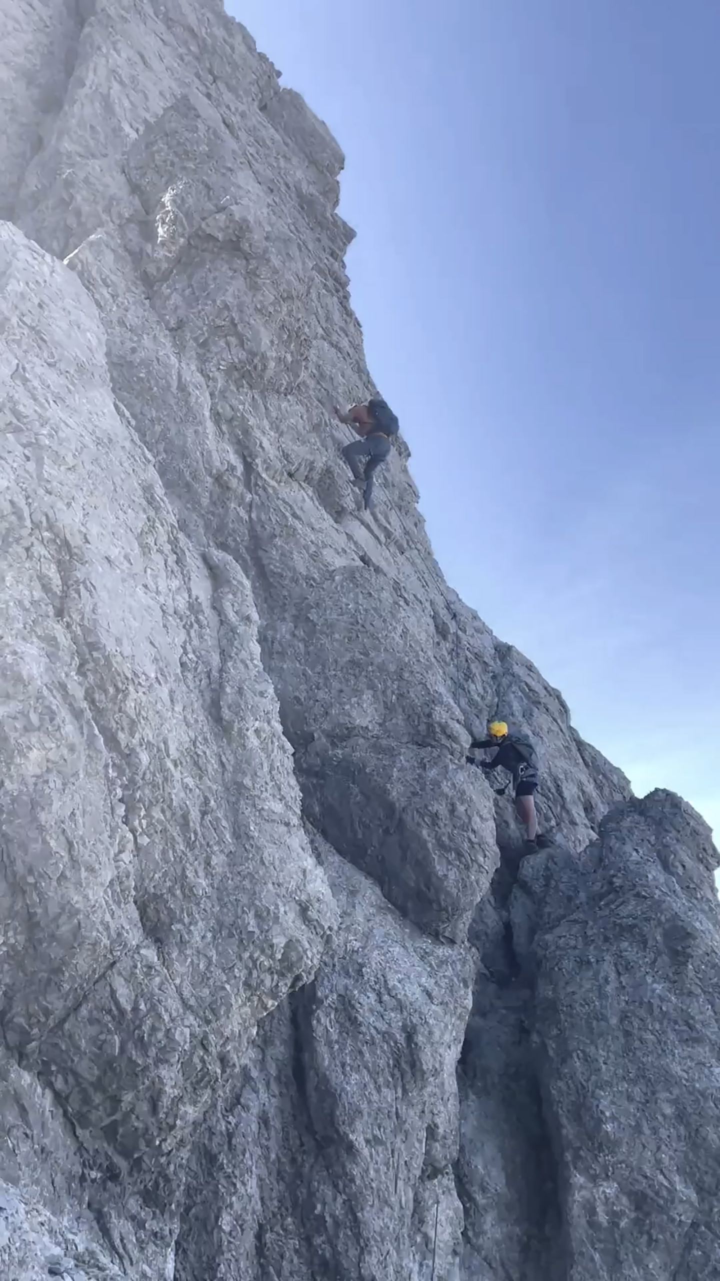 Two climbers in helmets on a rock face on the Arlberg via ferrata
