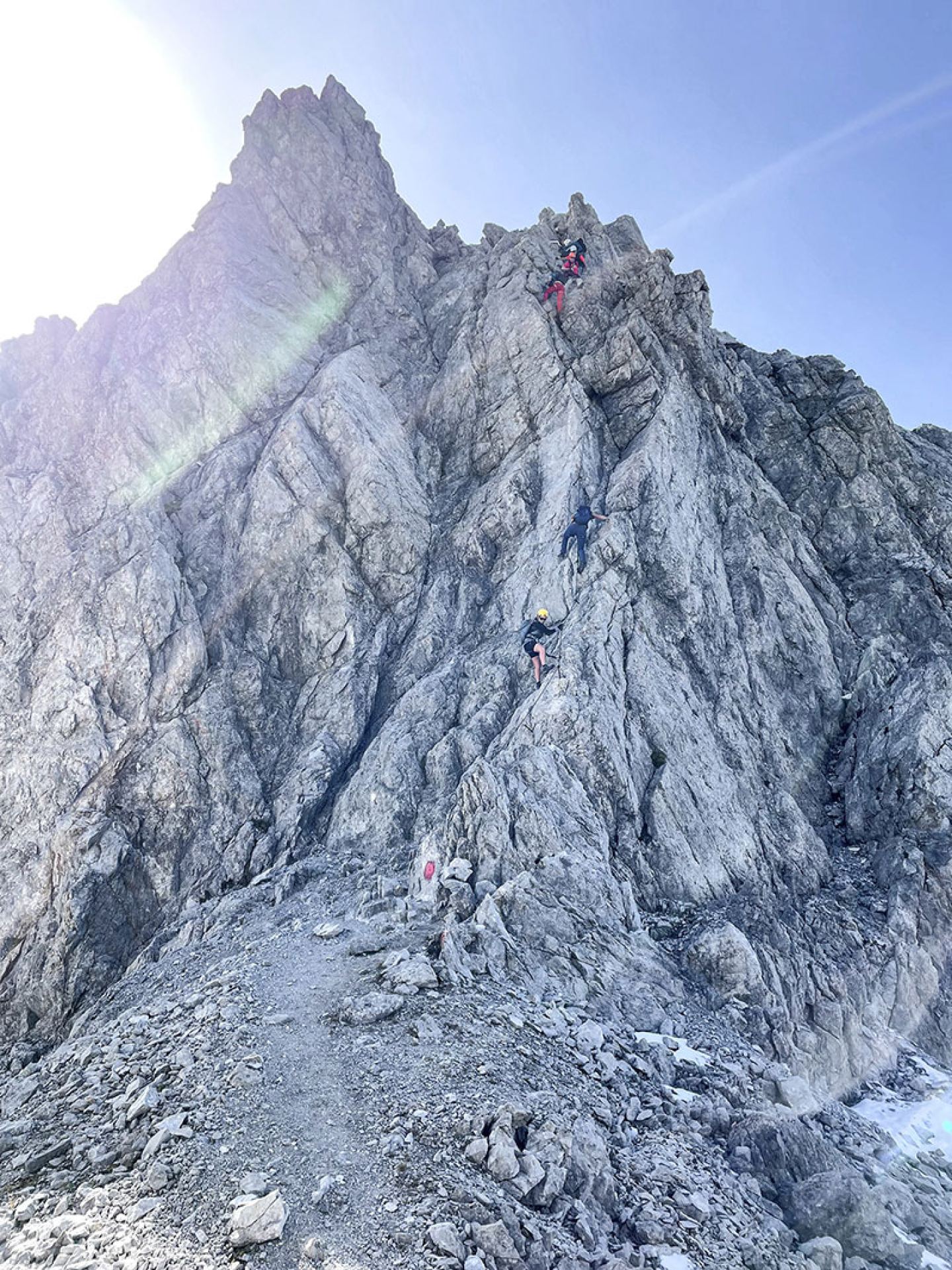 Two climbers on a sunlit rock face on the Arlberg via ferrata