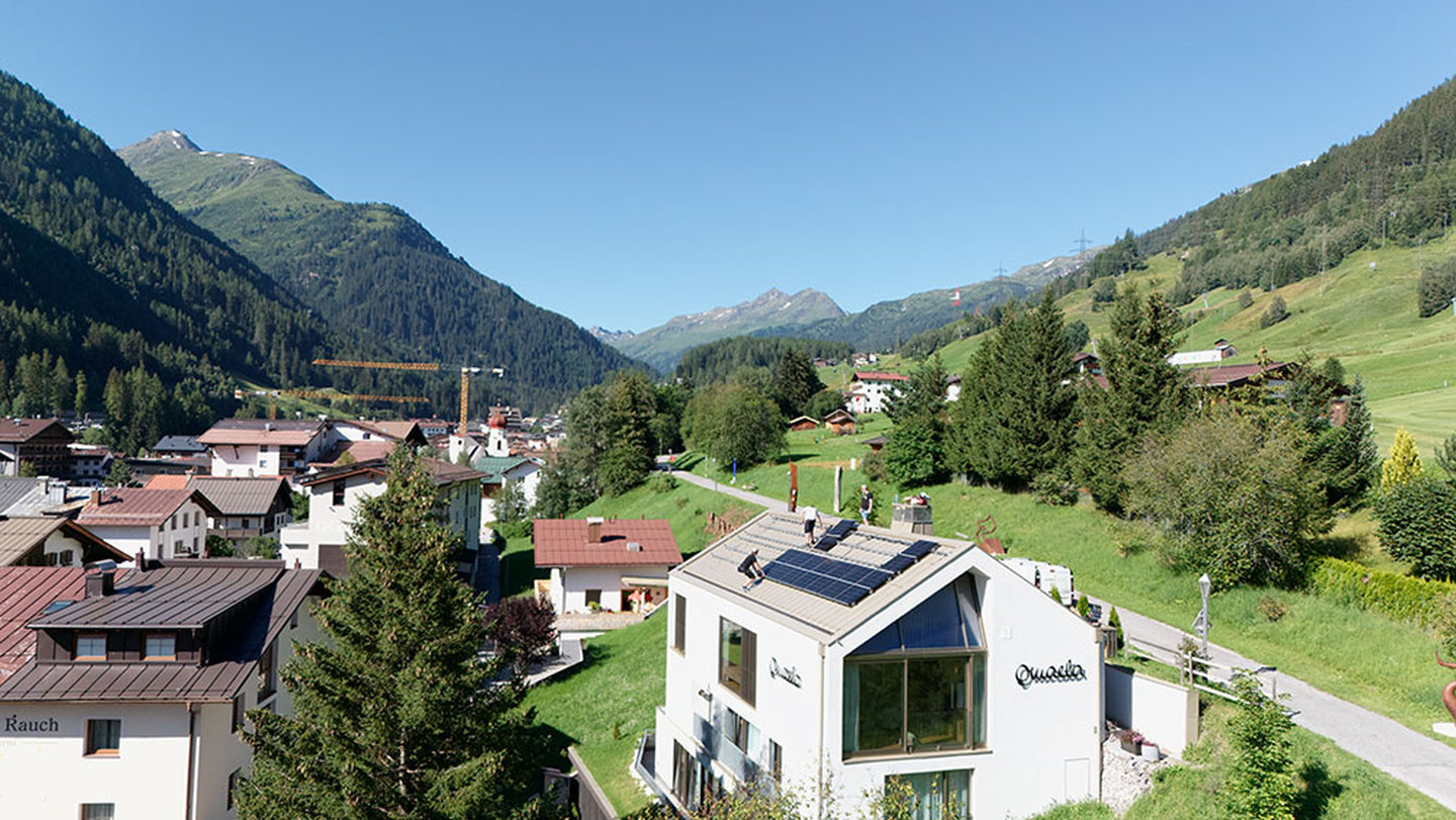 Aerial view of the Omaela Apartments with rooftop solar panels in the village of St. Anton am Arlberg in summer