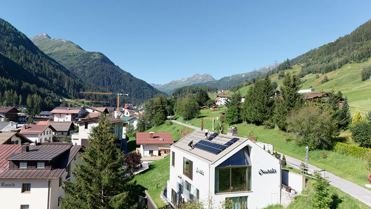Aerial view of the Omaela Apartments with rooftop solar panels in the village of St. Anton am Arlberg in summer