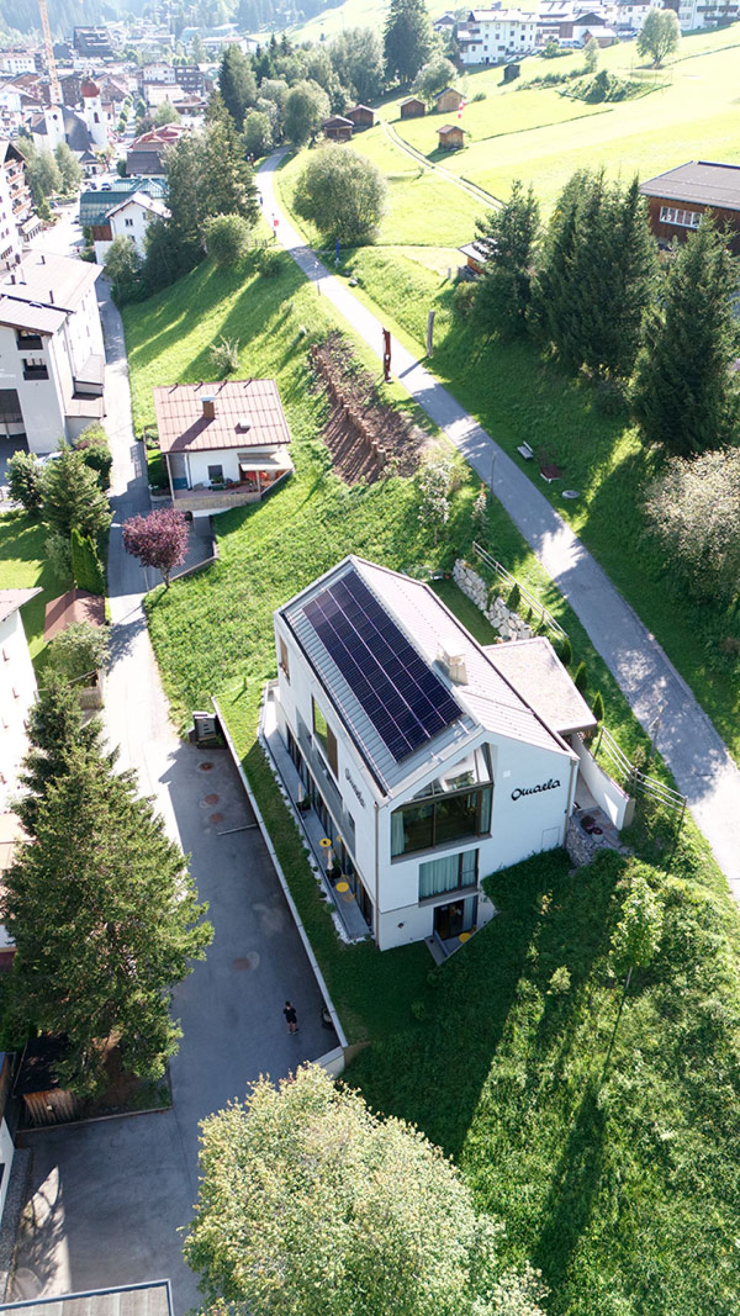 Aerial view of the Omaela Apartments with rooftop solar panels and green surroundings in St. Anton am Arlberg