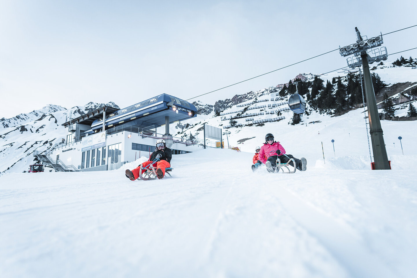 Zwei Personen rodeln im Schnee unterhalb der Bergstation am Arlberg