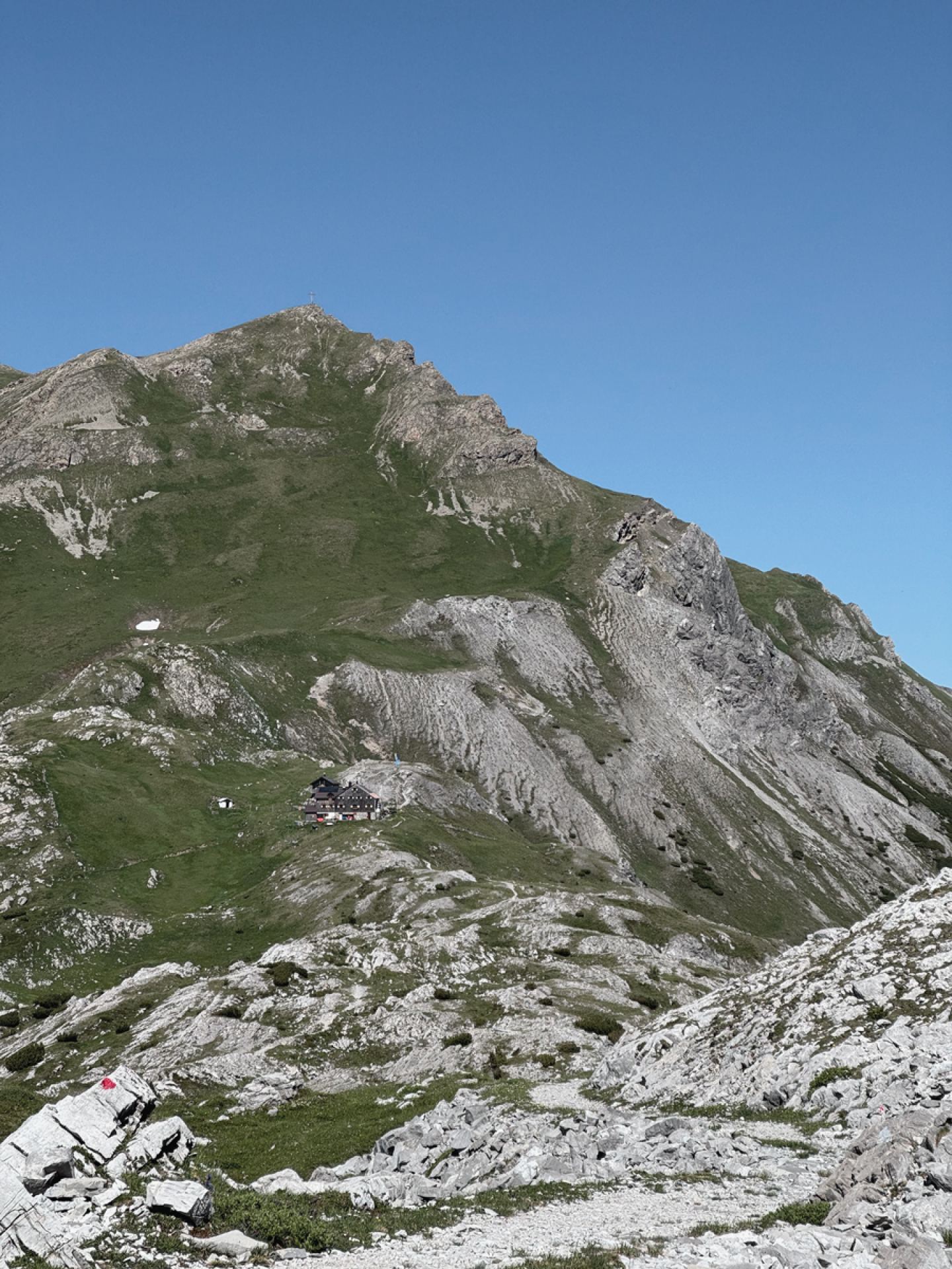 Leutkircher Hütte unterhalb eines felsigen Gipfels im Sommer am Arlberg