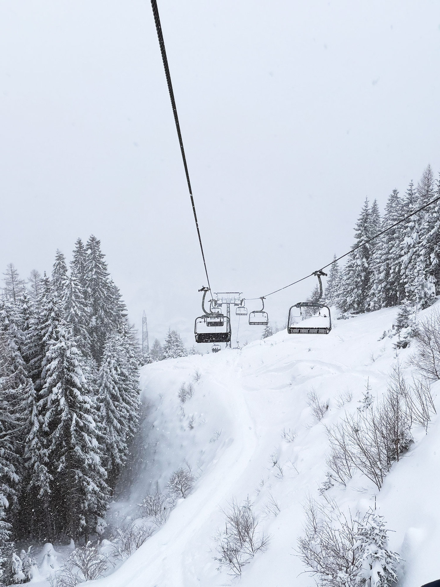 Blick den Sessellift hinauf durch verschneiten Wald im Schneefall am Arlberg