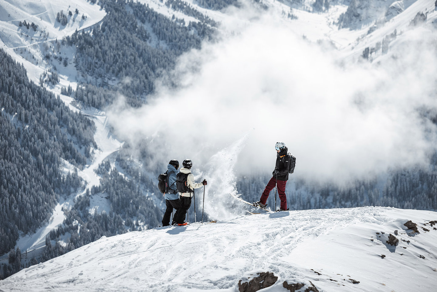 Drei Freerider auf einem verschneiten Grat über dem tiefen Tal am Arlberg