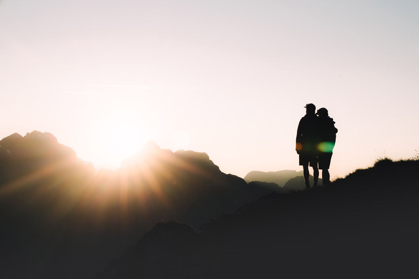 Zwei Wanderer als Silhouette bei Sonnenaufgang am Hirschpleiskopf-Grat am Arlberg